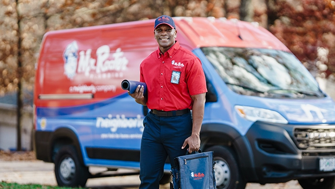 Mr. Rooter professional standing beside a branded work van.