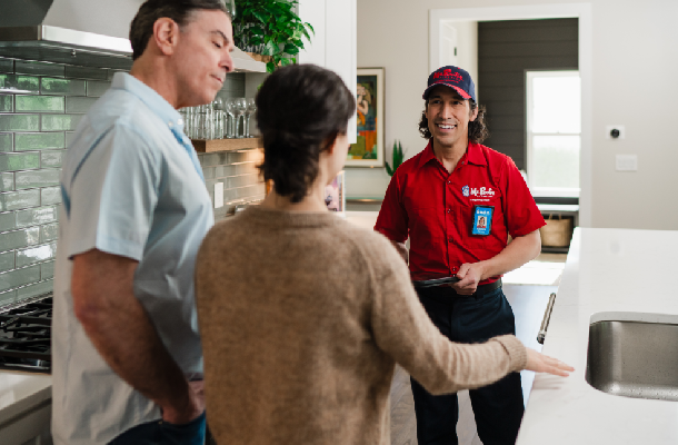 Mr. Rooter service professional talking to customers inside their home.