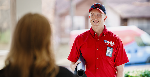 Mr. Rooter plumber standing in front of a customer.