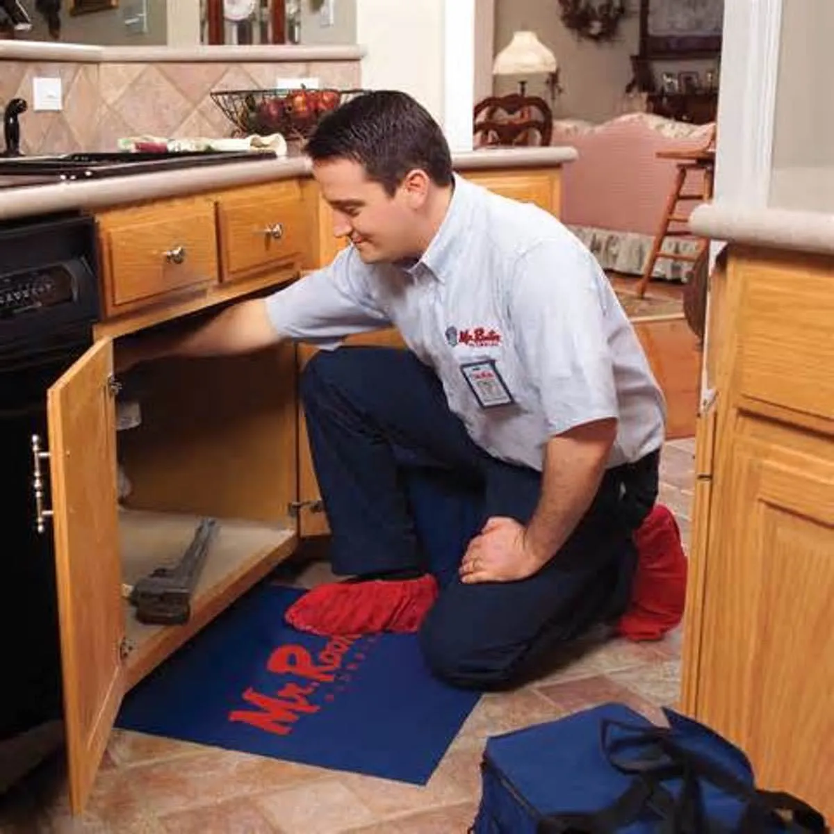 A plumber kneeling underneath a kitchen sink to complete faucet installation in Mississauga, ON.