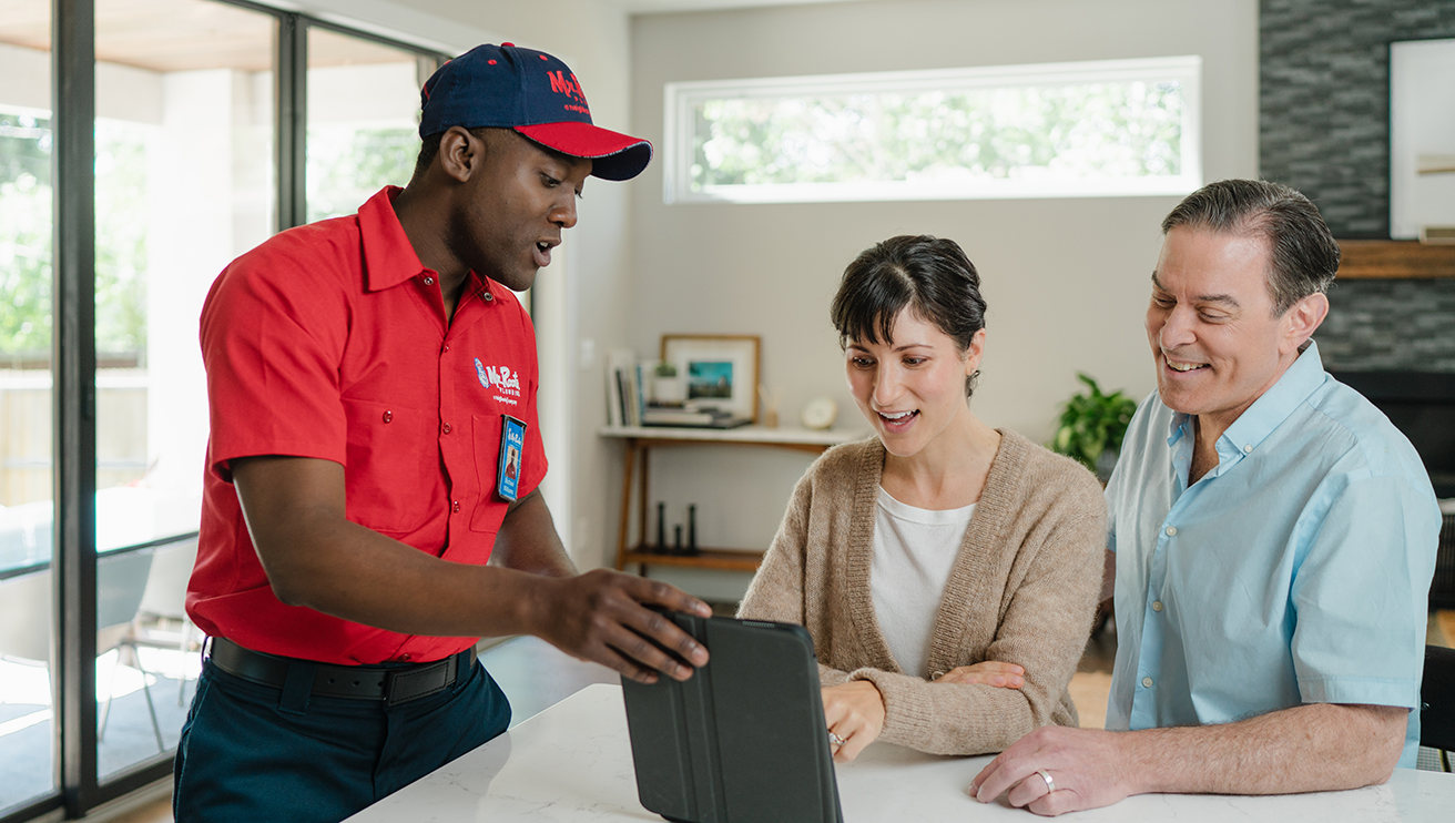 Mr. Rooter technician using a tablet to show a couple their service options.