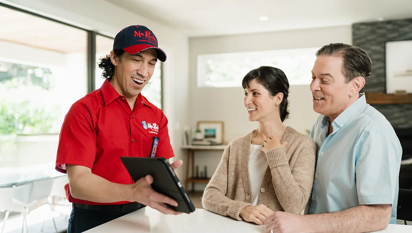 Mr. Rooter technician going over water softener service options with a customer on a tablet.