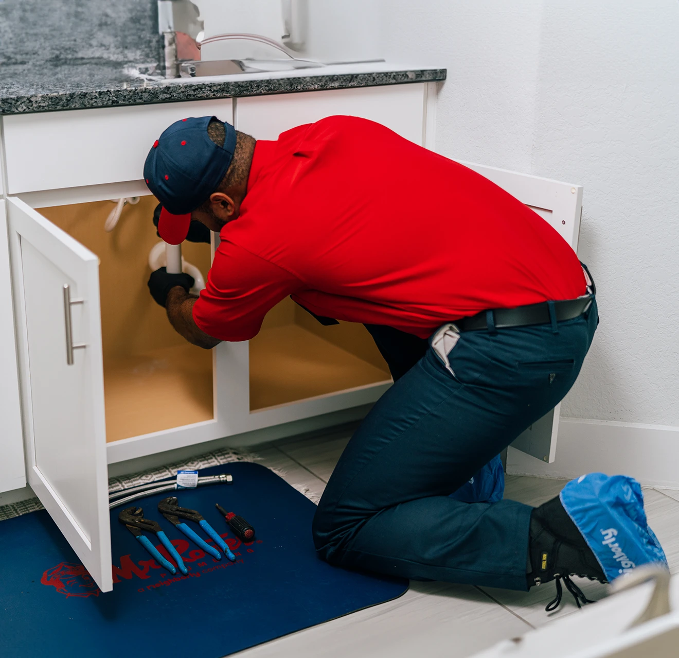 Mr. Rooter professional fixing a pipe underneath a sink.