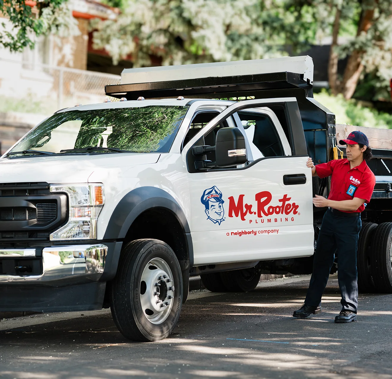 Mr. Rooter professional standing beside a branded white work truck.