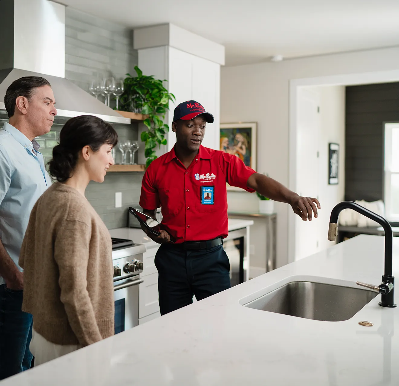 Mr. Rooter technician showing customers sink repair options in their kitchen.