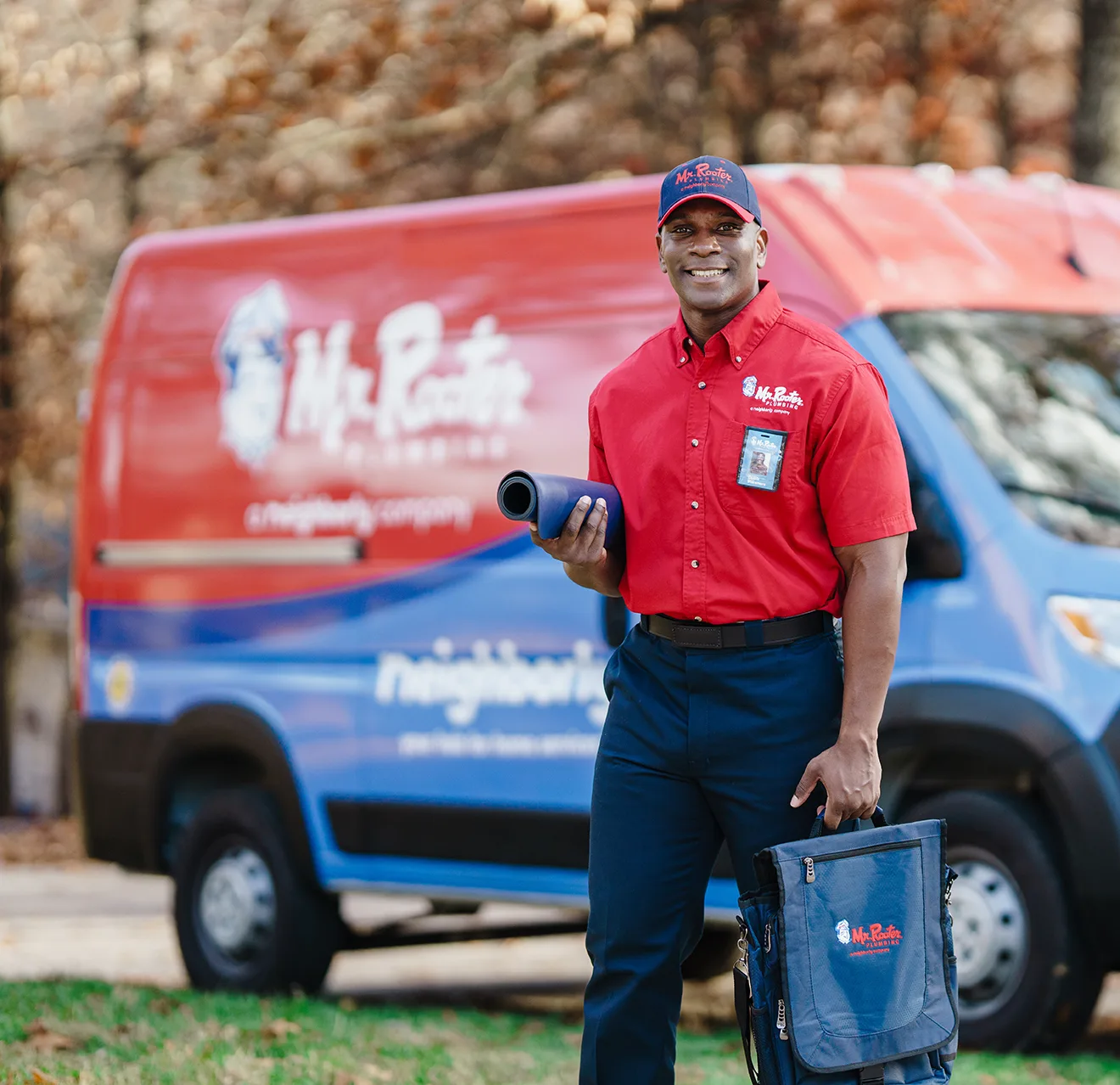 Mr. Rooter technician standing by a branded work van.