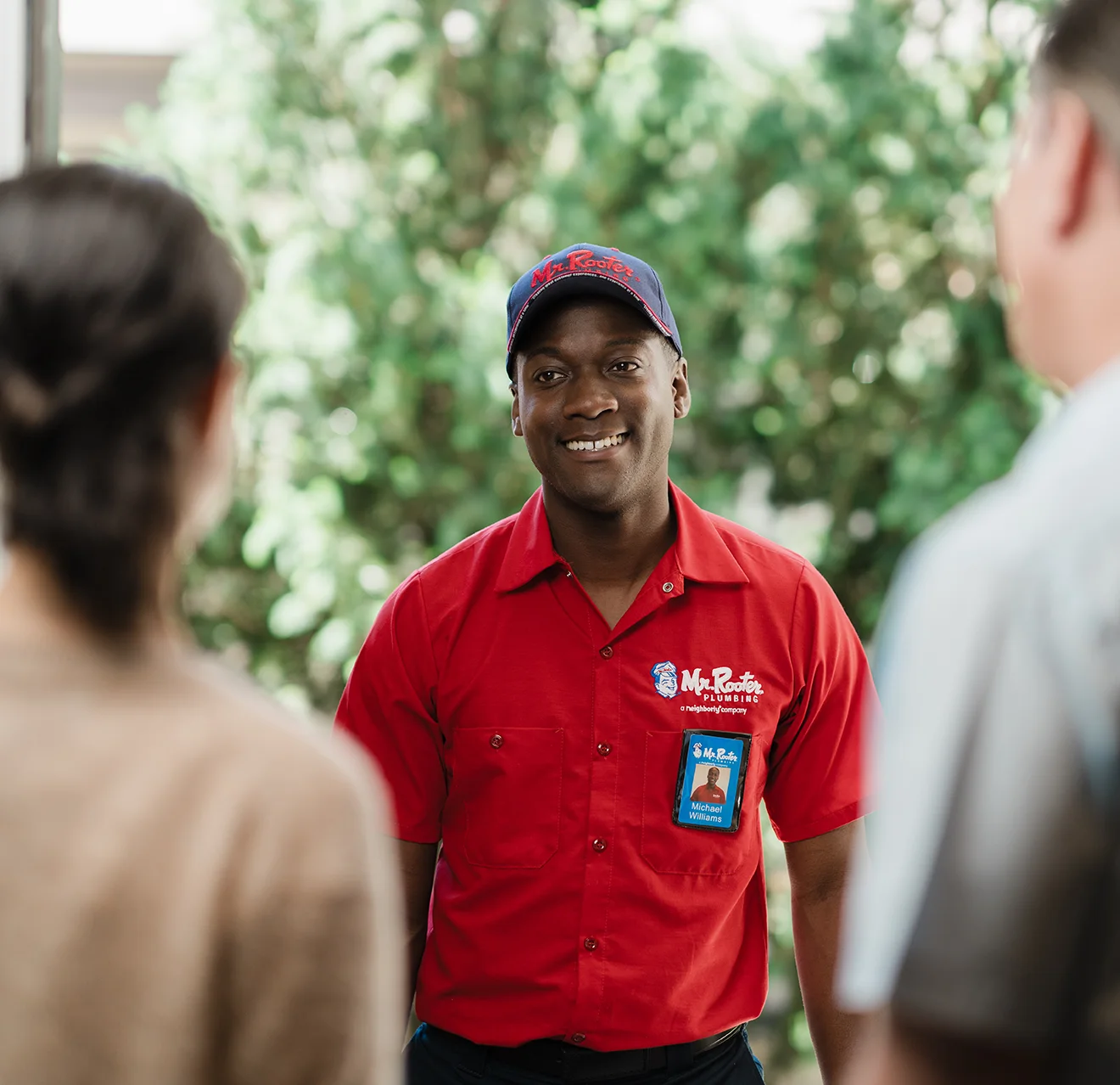 Two customers greeting a Mr. Rooter techician at their front door.