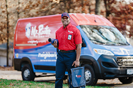 Mr. Rooter professional standing beside a branded work van.