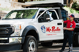 Mr. Rooter professional opening the door to a white branded work truck.