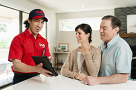 Mr. Rooter technician showing customers plumbing service options on a tablet.