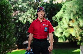 Mr. Rooter technician standing outside against a backdrop of greenery.