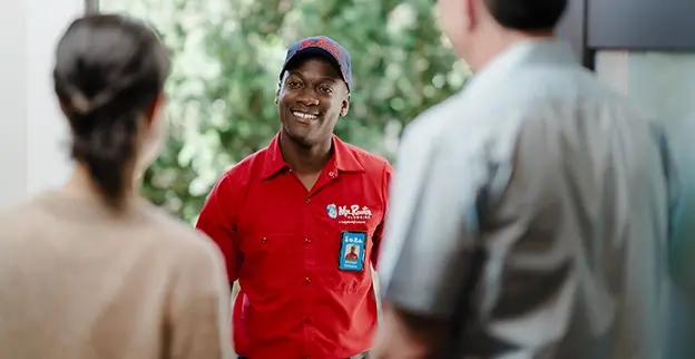 Two customers greeting a Mr. Rooter technician at their front door.