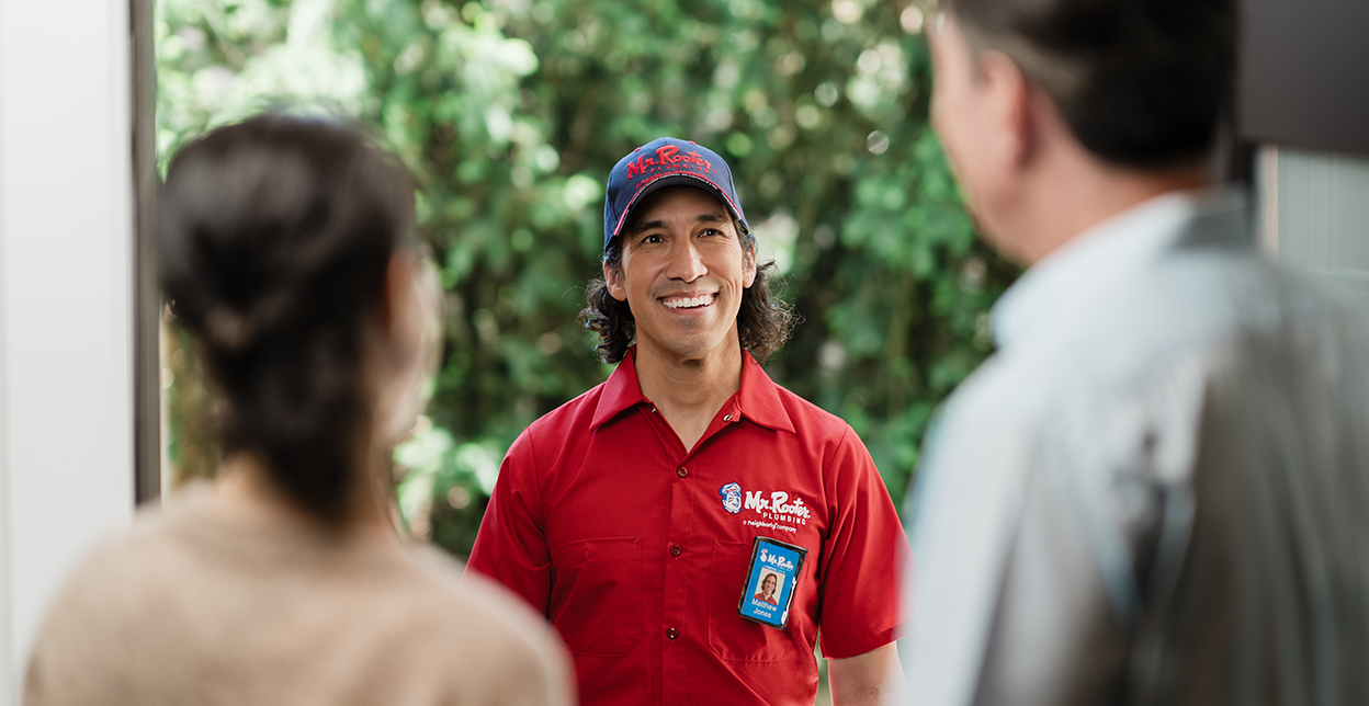 Mr. Rooter service technician being welcomed at a customer's door.