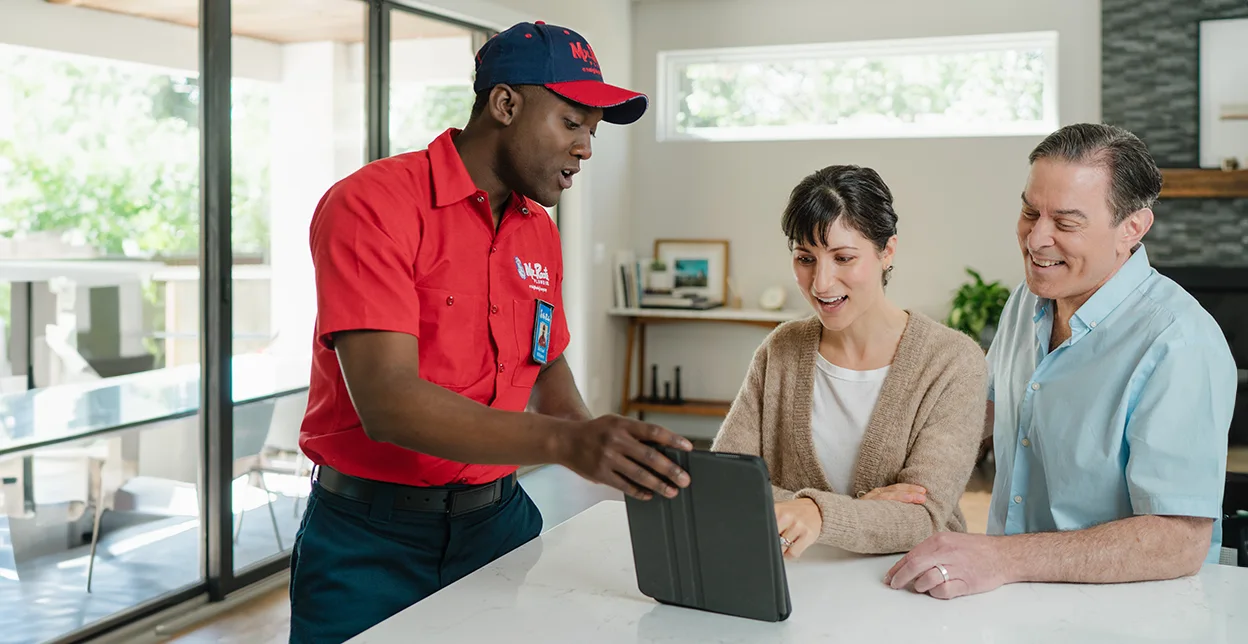 Mr. Rooter professional showing customers service options on a tablet.