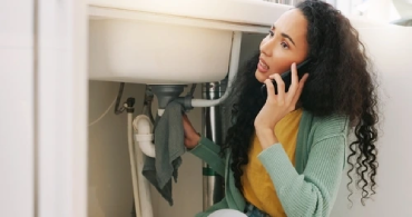 A woman calling professional plumbing services for a sink leak plumbing emergency.