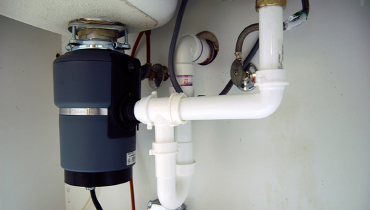 An installed garburator under a kitchen sink.