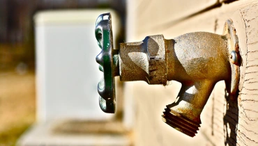 An old hose bib attached to the side of a home’s outer wall.