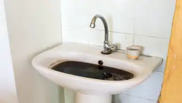 A clogged sink in Toronto filled with dirty water that has backed up into the basin of the sink.