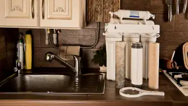 A home water treatment system with multiple chambers for filtration sitting on a counter with its filters before installation.