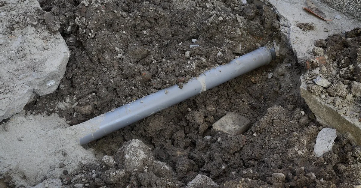 A dirt pit and a pipe underneath a concrete slab that has been broken apart to facilitate Ottawa main sewer line repair.