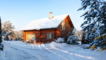 Small house in wooded area during winter with snow covering the ground