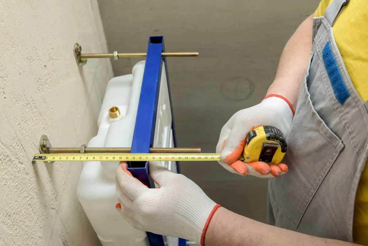 Calgary plumber measuring distance to properly perform toilet replacement.