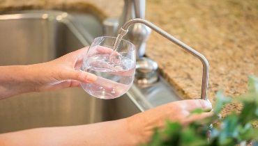 Glass of water being poured from a newly installed reverse osmosis water system in a Regina home