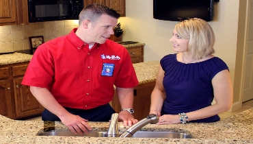 Mr. Rooter technician talking to female homeowner next to sink