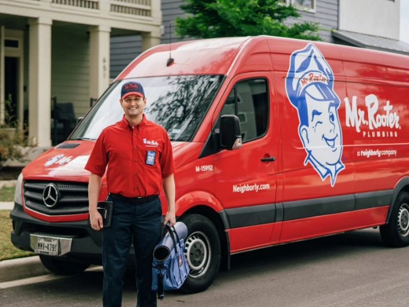 Mr. Rooter professional standing next to a branded van.