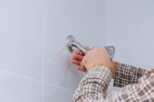 Hands replacing a bathroom shower head during a DIY plumbing upgrade.